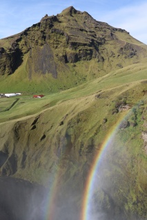 Waterfall spray spreads out over an idyllic Icelandic valley.